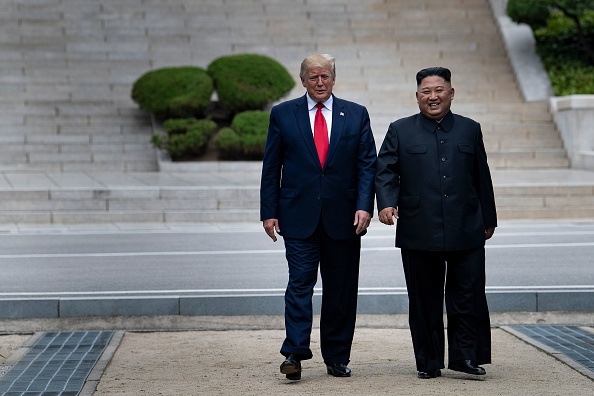 -Le président américain Donald Trump et le chef de la Corée du Nord Kim Jong-un marchent sur le sol nord-coréen en direction de la Corée du Sud dans la zone démilitarisée le 30 juin 2019 à Panmunjom en Corée. Photo par Brendan Smialowski / AFP / Getty Images.
