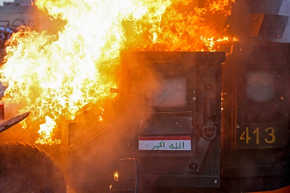 -Un véhicule de la police anti-émeute brûle lors d'affrontements pendant les manifestations contre la corruption de l'État, l'insuffisance des services publics et le chômage sur la place Tayeran Square, dans la capitale irakienne, le 3 octobre 2019. Photo par AHMAD AL-RUBAYE / AFP / Getty Images.