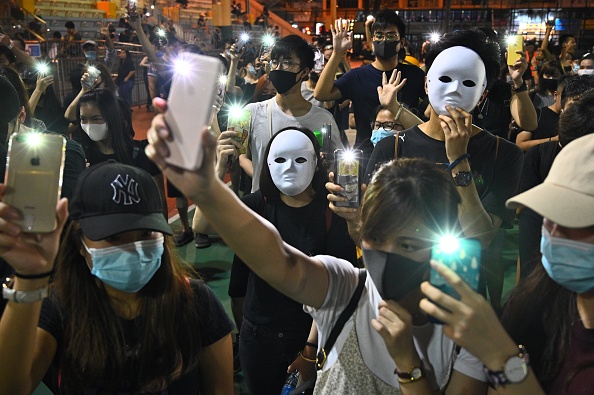 -Les gens portent des masques et allument leurs téléphones portables lors d'un rassemblement éclair dans le district de Sham Shui Po à Hong Kong le 5 octobre 2019, un jour après que le dirigeant de la ville ait interdit la couverture faciale lors de manifestations. Photo de Philip FONG / AFP / Getty Images.