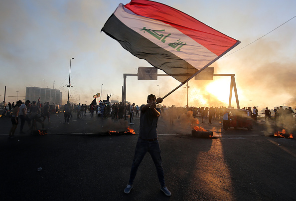 -Un manifestant irakien brandit le drapeau national lors d'une manifestation contre la corruption de l'Etat, les services publics défaillants et le chômage, à Bagdad, la capitale irakienne, le 5 octobre 2019. Photo par AHMAD AL-RUBAYE / AFP / Getty Images.