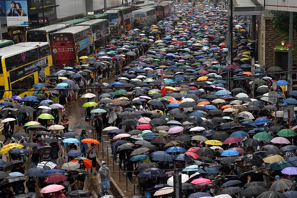 -Des personnes prennent part à une marche de protestation sous la pluie du quartier commerçant de Causeway Bay à Hong Kong le 6 octobre 2019. Un juge de Hong Kong a rejeté un recours en justice contre une loi d'exception criminalisant les manifestants portant des masques faciaux alors que des militants de la démocratie retournaient masqués dans les rues au mépris de l'interdiction. Photo de Nicolas ASFOURI / AFP / Getty Images.