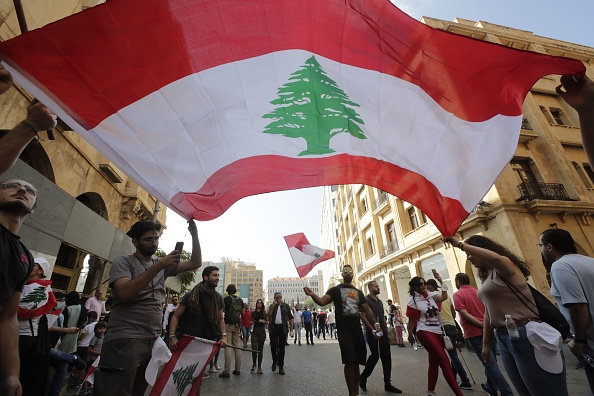 Les manifestants agitent le drapeau national au centre-ville de Beyrouth alors que des centaines de personnes continuent de se rassembler le 19 octobre 2019 pour une troisième journée de manifestations contre les augmentations d'impôts et la corruption. (Photo : ANWAR AMRO/AFP via Getty Images)