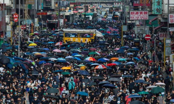 Les gens marchent le long de la route principale à Mong Kok alors qu'ils prennent part à une marche pro-démocratie de Tsim Sha Tsui dans le district de Kowloon à Hong Kong le 20 octobre 2019. (Philip Fong/AFP via Getty Images)