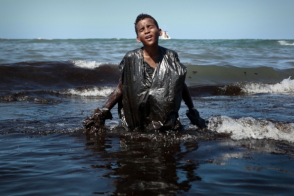 Image devenue virale d'un jeune garçon souillé par le pétrole. Plage d'Itapuama, ville de Cabo de Santo Agostinho, État de Pernambuco, Brésil, le 21 octobre 2019. (LEO MALAFAIA/AFP via Getty Images)