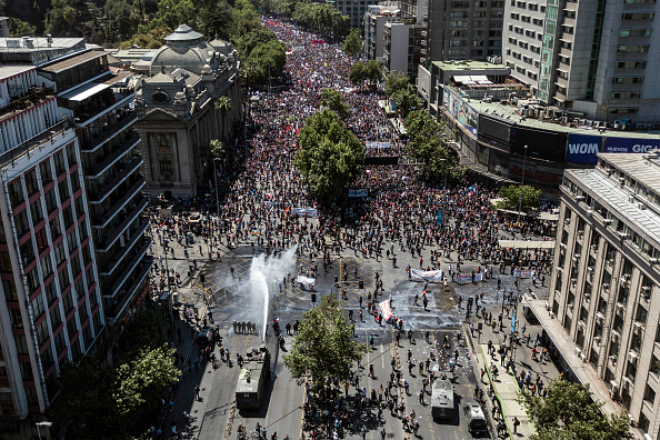 La police anti-émeute pulvérise de l'eau sur les manifestants à Santiago, le sixième jour consécutif de violences qui ont éclaté suite à une hausse maintenant suspendue du prix des tickets de métro, le 23 octobre 2019. (Photo : JAVIER TORRES/AFP via Getty Images)