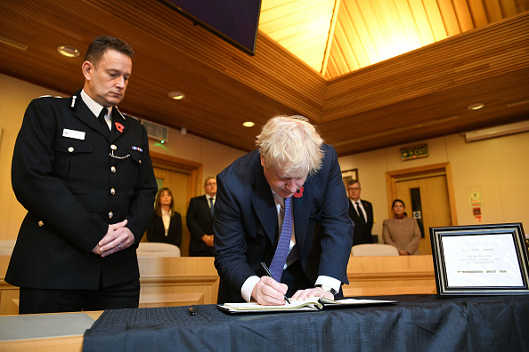 -Le Premier ministre britannique Boris Johnson signe un livre de condoléances lors de sa visite aux bureaux du conseil Thurrock à l'est de Londres, le 28 octobre 2019, à la suite de la découverte, le 23 octobre 2019, de 39 corps dissimulés dans un camion. Des familles vietnamiennes ont exprimé la crainte que leurs proches fassent partie des morts. Photo de STEFAN ROUSSEAU / POOL / AFP via Getty Images.
