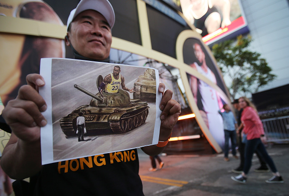 Un activiste pro-Hong Kong détient une image représentant LeBron James à bord d'un tank chinois sur la place Tiananmen avant le match d'ouverture de la saison des Los Angeles Lakers contre les LA Clippers devant le Staples Center le 22 octobre 2019 à Los Angeles, en Californie. (Photo : Mario Tama/Getty Images)