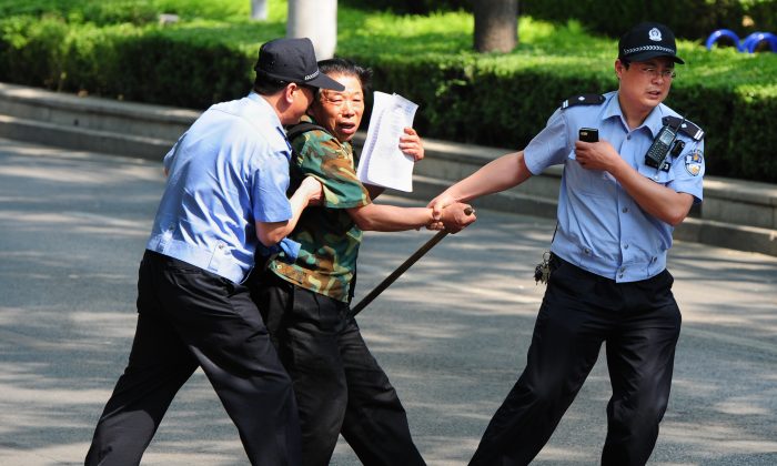 Un pétitionnaire est détenu par la police à l'extérieur de l'hôpital Chaoyang, où un groupe de personnes proteste contre les problèmes médicaux et l'accaparement des terres à pékin le 8 mai 2012. (Mark Ralston/AFP/GettyImages)