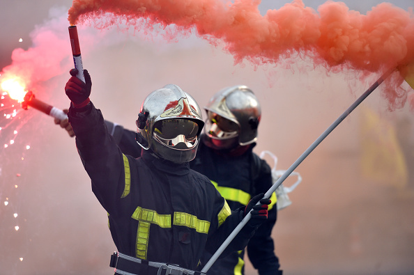 Les pompiers brandissent des flambées de fumée lors d'une manifestation sur la Place de la Nation à Paris le 24 novembre 2016 dans le cadre d'une grève nationale pour dénoncer la violence contre les pompiers qui font leur travail, les compressions budgétaires et la réduction des effectifs.     (Photo : ALAIN JOCARD/AFP/Getty Images)