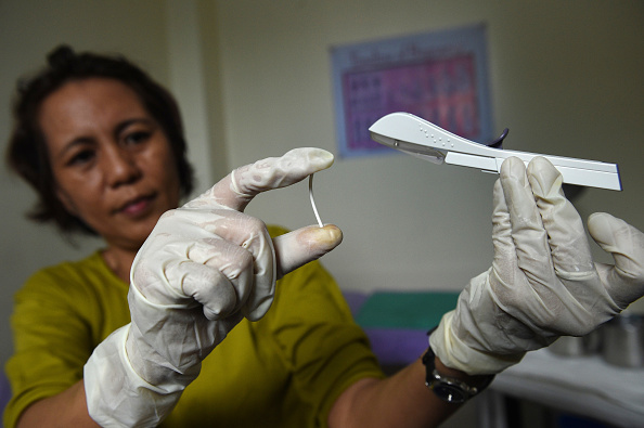 Une infirmière montre un échantillon d'un implant contraceptif.      (Photo : TED ALJIBE/AFP via Getty Images)