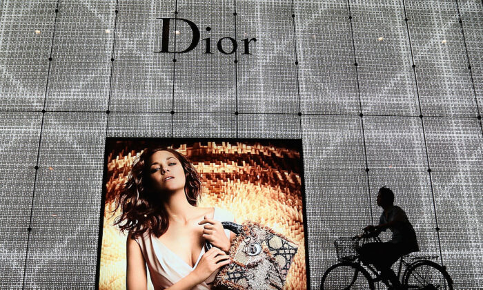 Le 8 juin 2012, un homme passe devant une publicité pour le magasin Christian Dior de Pékin à vélo. (Feng Li/Getty Images)

