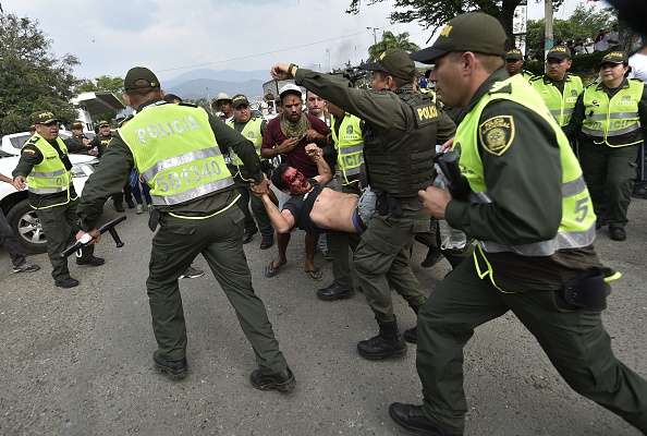 -Illustration- Des policiers transportent un manifestant blessé lors d'affrontements. Photo de Luis ROBAYO / AFP via Getty Images.