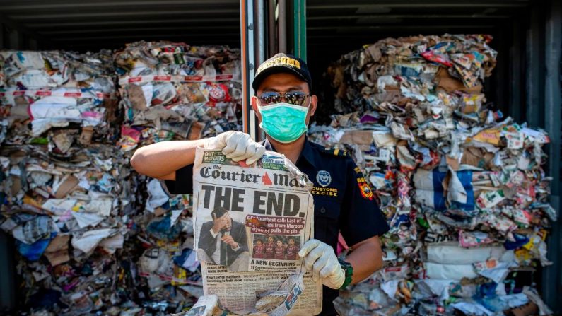 Un douanier indonésien ramasse un journal dans un conteneur rempli de déchets provenant d'Australie le 9 juillet 2019. (JUNI KRISWANTO / AFP / Getty Images)