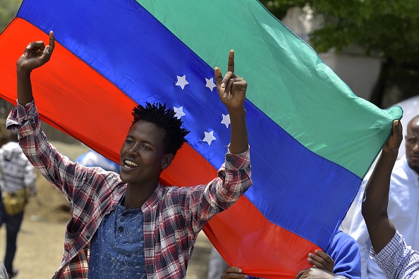 -Un jeune homme réagit devant le drapeau vert, bleu et rouge non officiel de la région défendue par le groupe ethnique Sidama. Photo de Michael TEWELDE / AFP via Getty Images.