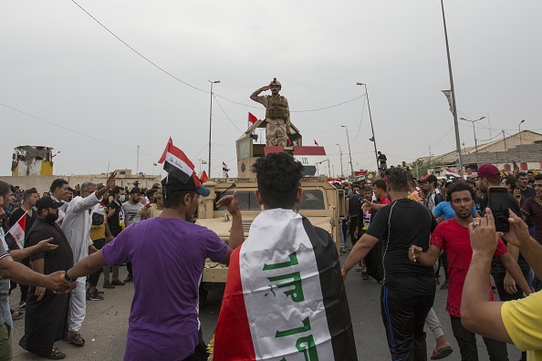 -Un soldat de l'armée irakienne debout salue les manifestants rassemblés lors d'une manifestation antigouvernementale devant le siège du gouvernement local dans la ville de Basra, dans le sud du pays, le 25 octobre 2019. Photo by - / AFP via Getty Images.