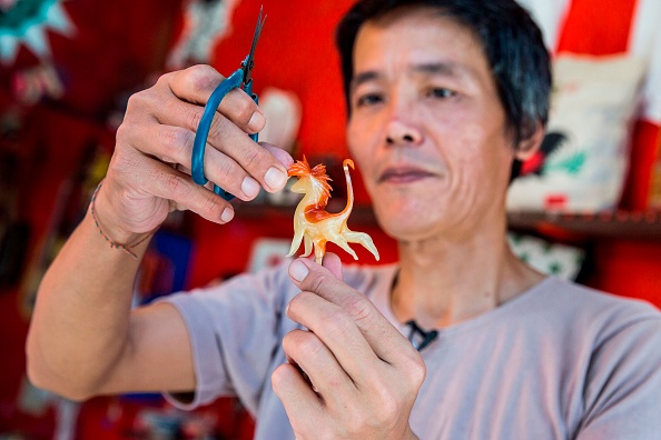 -Cette photo prise le 6 juin 2019 montre le commerçant Louis To en train de confectionner un bonbon en forme de figurine dans son magasin de l'île de Cheung Chau à Hong Kong. Photo ISAAC LAWRENCE / AFP via Getty Images.