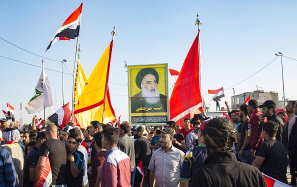 -Des manifestants irakiens portent des drapeaux et une image du religieux chiite, l'ayatollah Ali Husaini al-Sistani, lors des manifestations antigouvernementales en cours dans la ville de Basra, dans le sud du pays, le 1er novembre 2019. Photo de HUSSEIN FALEH / AFP via Getty Images.