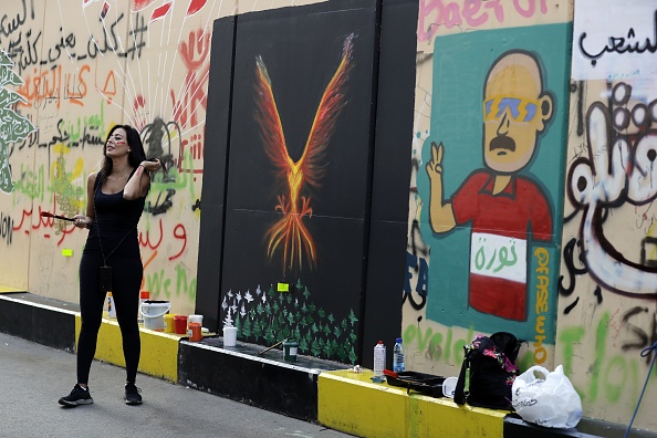 -L'artiste libanaise et manifestante anti-gouvernementale, Hayat Nazer, se tient le 6 novembre 2019 à côté de sa fresque en phénix dans le quartier du centre-ville de Beyrouth. Photo de JOSEPH EID / AFP via Getty Images.