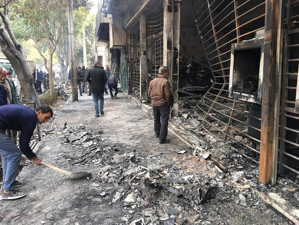 Les Iraniens passent devant une banque carbonisée incendiée lors d'une manifestation contre la hausse des prix de l'essence dans la ville Ispahan le 17 novembre 2019. (Photo : AFP via Getty Images)