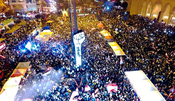 Des manifestants libanais se rassemblent autour d'un nouveau signe géant de poing qui porte le mot arabe "révolution", sur la Place des Martyrs de la capitale libanaise, le 22 novembre 2019. Le signe a été brûlé pendant la nuit par des inconnus.(Photo : AFP via Getty Images)