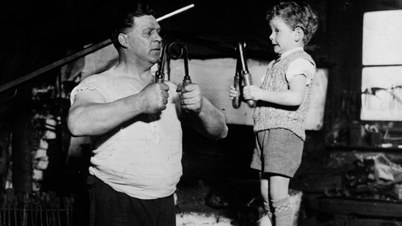 Un jeune garçon et son père développent leurs muscles. Fox Photos/Getty Images