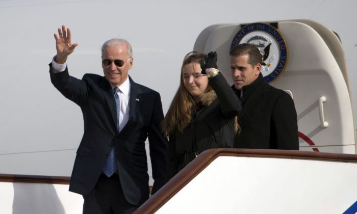 Joe Biden, vice-président américain de l'époque, salue le comité d’accueil chinois en sortant de l’avion avec sa petite-fille Finnegan Biden et son fils Hunter Biden à l'aéroport de Pékin, le 4 décembre 2013. (Ng Han Guan-Pool/Getty Images)