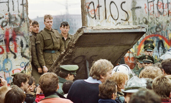 Les Berlinois de l’ouest se rassemblent devant le mur de Berlin au début de la journée du 11 novembre 1989 alors qu’ils observent les gardes-frontières est-allemands démolir une partie du mur. (Gerard Malie / AFP via Getty Images)