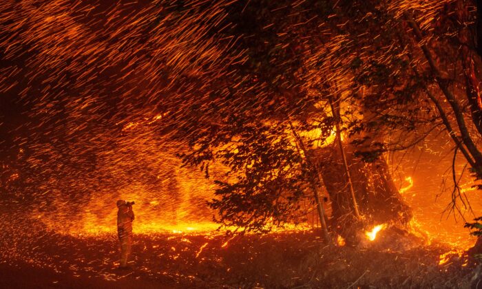 Un photographe prend des photos au milieu d'une pluie de braises alors que le vent et les flammes ravagent la région pendant l'incendie de Kincade près de Geyserville, Californie, le 24 octobre 2019. (Josh Edelson/AFP via Getty Images)