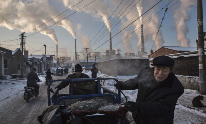 Des Chinois tirent un tricycle tandis que la fumée s'échappe des cheminées d'une centrale au charbon à Shanxi, en Chine, le 26 novembre 2015. (Kevin Frayer/Getty Images)
