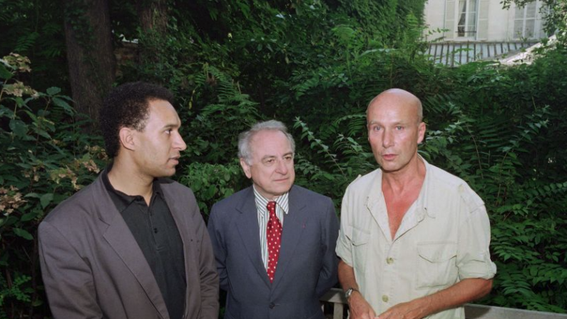 Le 12 juillet 1990, le président de l'association française SOS Racisme Harlem Desir, l'homme d'affaires et mécène français Pierre Bergé et l'écrivain français Gabriel Matzneff posant dans le jardin de la "Maison des Ecrivains" à Paris, lors de leur première anniversaire de la Maison chinoise de la démocratie. (PIERRE GUILLAUD / AFP via Getty Images)
