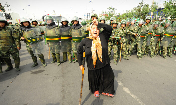 La police antiémeute chinoise regarde les protestations d'une femme ouïgour musulmane à Urumqi, dans la province du Xinjiang, à l'extrême ouest de la Chine. (Getty Images | PETER PARKS)