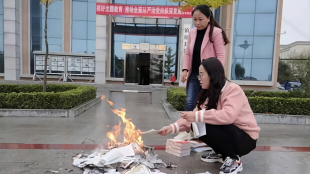 Deux travailleurs sont vus en train de brûler des livres devant la bibliothèque du comté de Zhenyuan dans la ville de Qingyang, province du Gansu, le 22 octobre 2019. (Site officiel du comté de Zhenyuan) 