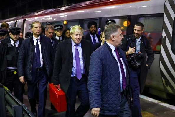 -Le Premier ministre britannique Boris Johnson marche le long de la plate-forme après son arrivée à la gare de Londres Euston, dans le centre de Londres, le 4 décembre 2019. Photo de HANNAH MCKAY / POOL / AFP via Getty Images.