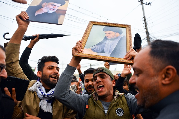 -Des partisans du religieux irakien Moqtada Sadr ont levé des photos de lui lors d'un rassemblement près de sa résidence dans la ville centrale de Najaf, le 7 décembre 2019. Un drone armé a visé le domicile du religieux irakien Moqtada Sadr samedi, quelques heures après ses partisans déployé à Bagdad en réponse à une attaque qui a fait 17 morts. Photo de HAIDAR HAMDANI / AFP via Getty Images.