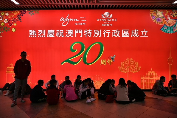-Des enfants participant à la cérémonie de bienvenue du président chinois Xi Jinping attendent devant un affichage célébrant le 20e anniversaire du transfert du Portugal vers la Chine, à l'aéroport international de Macao le 18 décembre 2019. Photo par ANTHONY WALLACE / AFP via Getty Images.