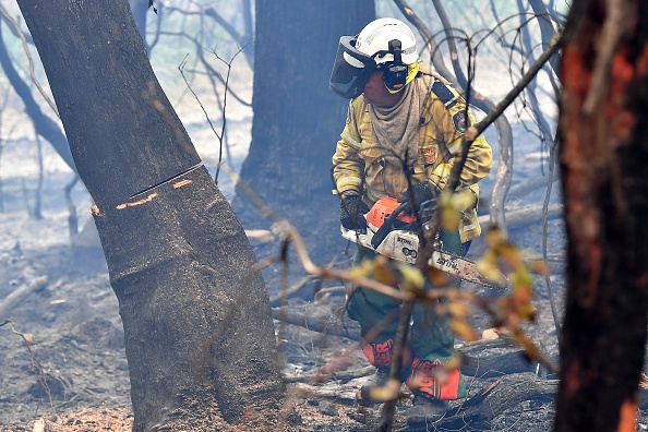 -Le 18 décembre 2019 le pompier volontaire Andrew Moyle coupe des arbres brûlés à Dargan, à environ 120 kilomètres de Sydney. Photo par SAEED KHAN / AFP via Getty Images.