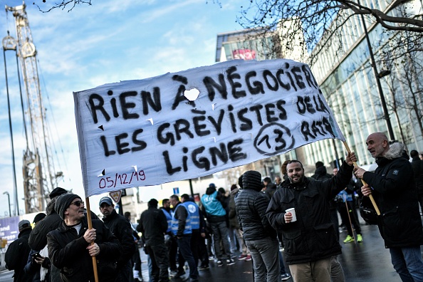 Le 24 décembre 2019, les salariés de la RATP brandissent une banderole devant le siège de la SNCF à Saint-Denis à l'occasion de la 20e journée d'un mouvement national sur le projet de la réforme des retraites. (Photo : STEPHANE DE SAKUTIN/AFP via Getty Images)