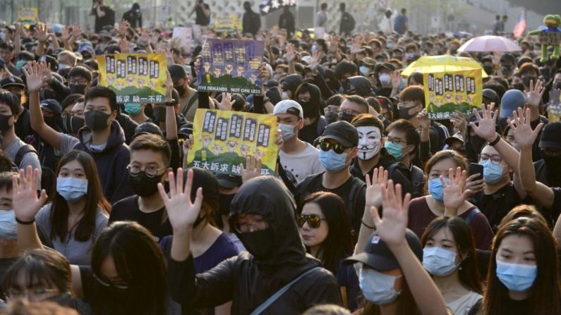 Des manifestants lèvent la main pour signaler leurs cinq revendications lors d'une marche à Tsim Sha Tsui, Hong Kong, le 1er décembre 2019. (Gordan Yu/The Epoch Times)