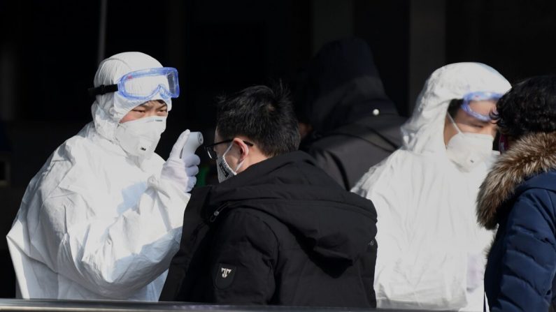 Les voyageurs sont contrôlés par le personnel de sécurité vêtu de combinaisons de protection contre les matières dangereuses à l'entrée de la station de métro de Pékin le 24 janvier 2020. (Noel Celis/AFP via Getty Images)