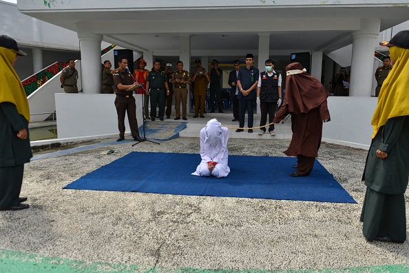 -Une femme est fouettée par un membre de la police de la charia en public à Banda Aceh le 10 décembre 2019, après avoir été arrêtée à proximité d'un homme qui n'est pas son mari dans un hôtel. Photo de CHAIDEER MAHYUDDIN / AFP via Getty Images.