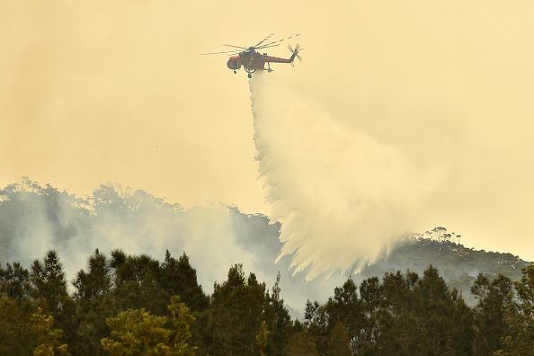-Un hélicoptère largue de l'eau sur un feu de brousse à l'extérieur de Batemans Bay en Nouvelle-Galles du Sud le 2 janvier 2020. Photo de PETER PARKS / AFP via Getty Images.