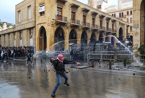 Un manifestant antigouvernemental jette un rocher sur les forces de sécurité alors qu'elles tirent des canons à eau lors d'affrontements dans le centre-ville de Beyrouth,  près du siège du Parlement, le 18 janvier 2020. (Photo : ANWAR AMRO/AFP via Getty Images)