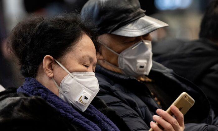 Les voyageurs portant des masques de protection se reposent sur un banc après leur arrivée à l'aéroport de la capitale, Pékin, le 21 janvier 2020. (NOEL CELIS/AFP via Getty Images)