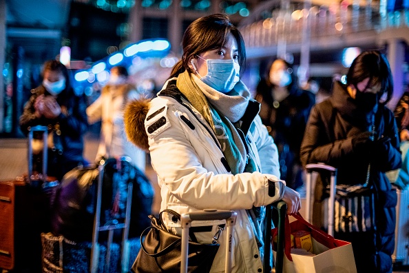Une femme portant un masque de protection arrive à la gare de Pékin avant le nouvel an à Pékin le 23 janvier 2020. La Chine arrête les transports publics et ferme les péages des autoroutes dans deux autres villes de la province du Hubei, l'épicentre d'une épidémie mortelle de virus, ont annoncé les autorités le 23 janvier. (Photo : NOEL CELIS/AFP via Getty Images)