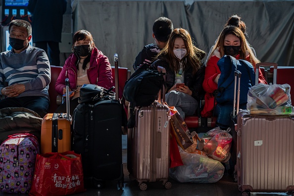 Des personnes portant des masques de protection attendent de monter à bord de leur train pendant leur voyage pour les vacances du Nouvel An à la gare de Beijing West à Pékin le 24 janvier 2020. (Photo : NICOLAS ASFOURI/AFP via Getty Images)