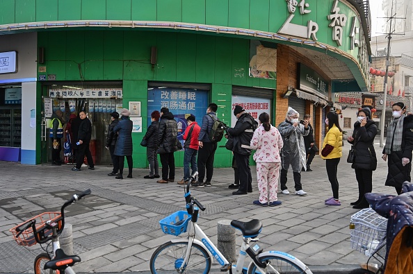 Des personnes portant des masques protecteurs se trouvent à côté d'une pharmacie à Wuhan, dans la province du Hubei, le 30 janvier 2020. (Photo : HECTOR RETAMAL/AFP via Getty Images)