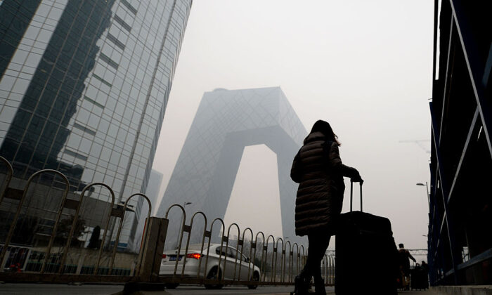 This picture taken on Une femme passe à côté de la tour CCTV, dans le brouillard de pollution de Pékin (STR/AFP via Getty Images)