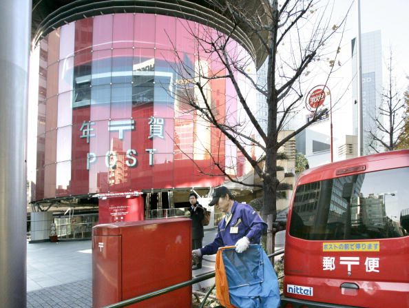 -Un facteur ramasse du courrier à côté d'une boîte aux lettres de 20 mètres de haut, qui est une entrée d'une station de métro avec une boîte aux lettres régulière dans sa porte principale, à Tokyo le 15 décembre. 2008. Photo YOSHIKAZU TSUNO / AFP via Getty Images.
