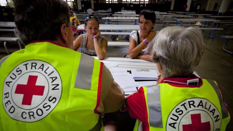 Les résidents de la ville de St George; Deanne Lasserre (en haut en gauche), 27 ans, et sa mère Rosemarie (en haut à droite) sont assistés par des bénévoles de la Croix-Rouge au centre d'évacuation de la ville de Brisbane, dans l'État du Queensland, en Australie, le 7 février 2012. (PATRICK HAMILTON/AFP via Getty Images) 