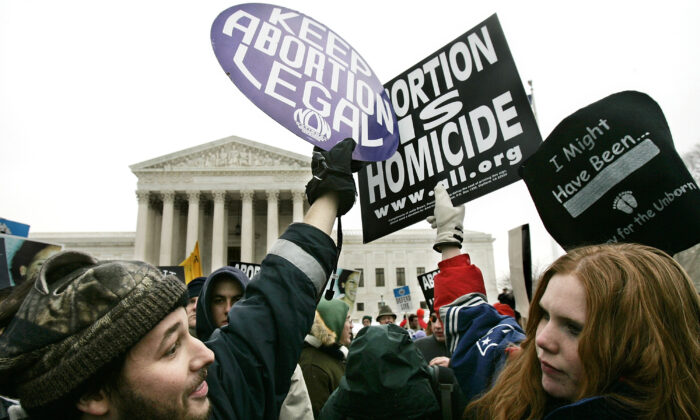 La militante pro-vie Jessica Meunier (à droite) de Fitchburg, MA, et le militant pro-avortement Luqman Clark (à gauche) d'Arlington, VA, tiennent des pancartes alors qu'ils protestent devant la Cour suprême des États-Unis lors de l'événement « March for Life » du 24 janvier 2005 à Washington, D.C. Images par Alex Wong / Getty images